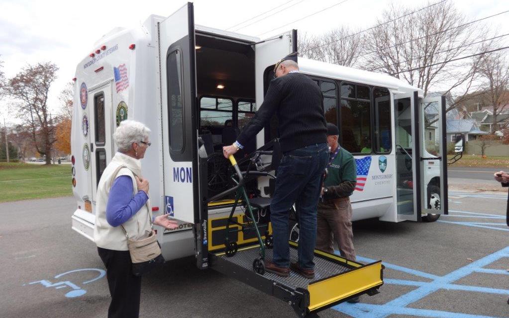 Following the county's ceremony to unveil the new Veterans Mini-Bus, veteran Garth MacFarland tries out the handicapped-accessible feature, while his wife, Nancy MacFarland, left, looks on.
