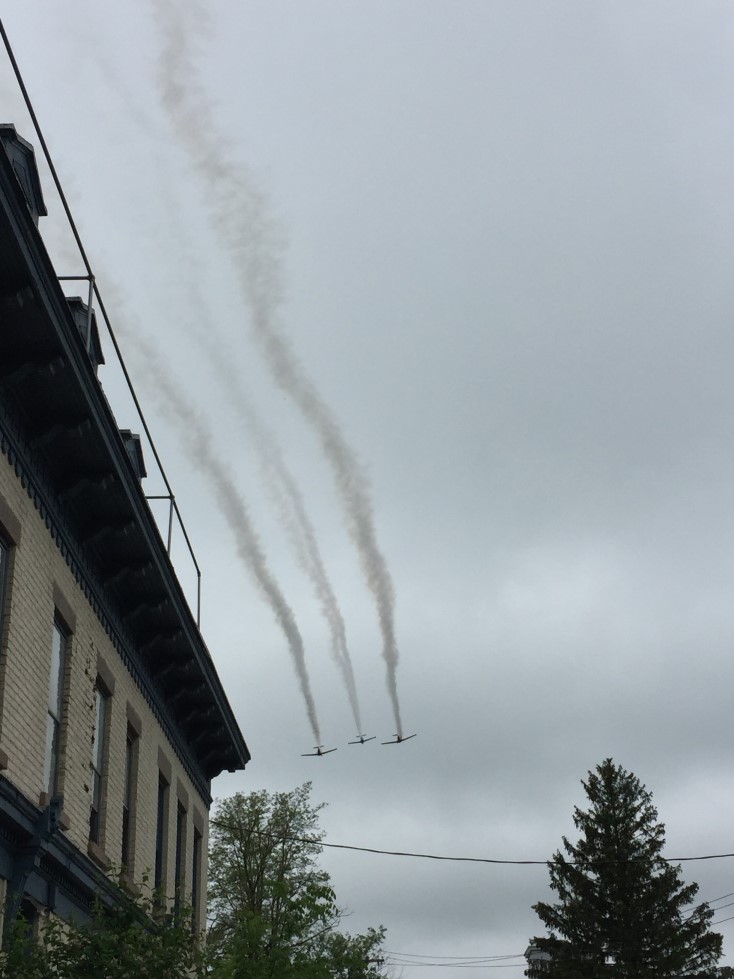 Three planes flying in the sky, next to a building