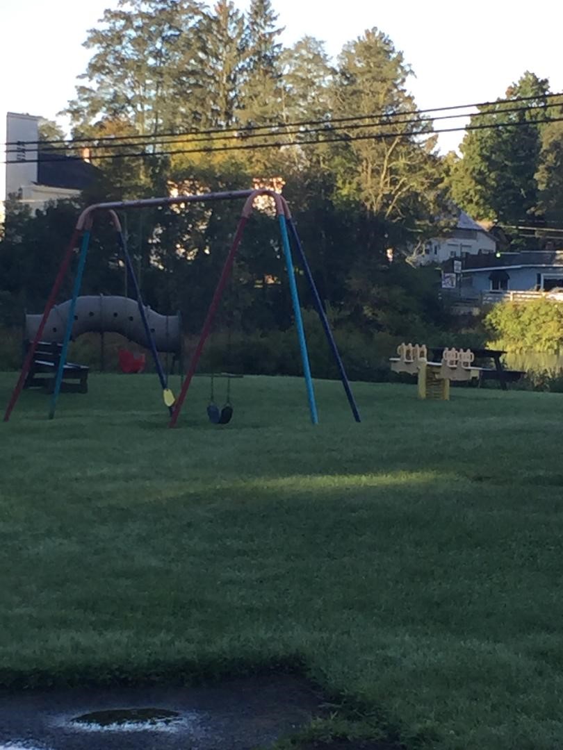 Playground equipment in the park on a summer day - swingset and climbing equipment in the background